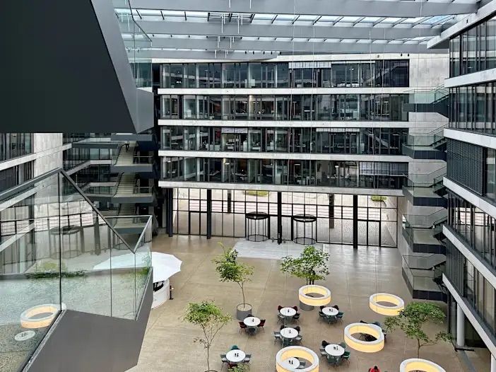 Moderne Bürohalle mit Atrium, Glasfassaden und offenen Sitzbereichen